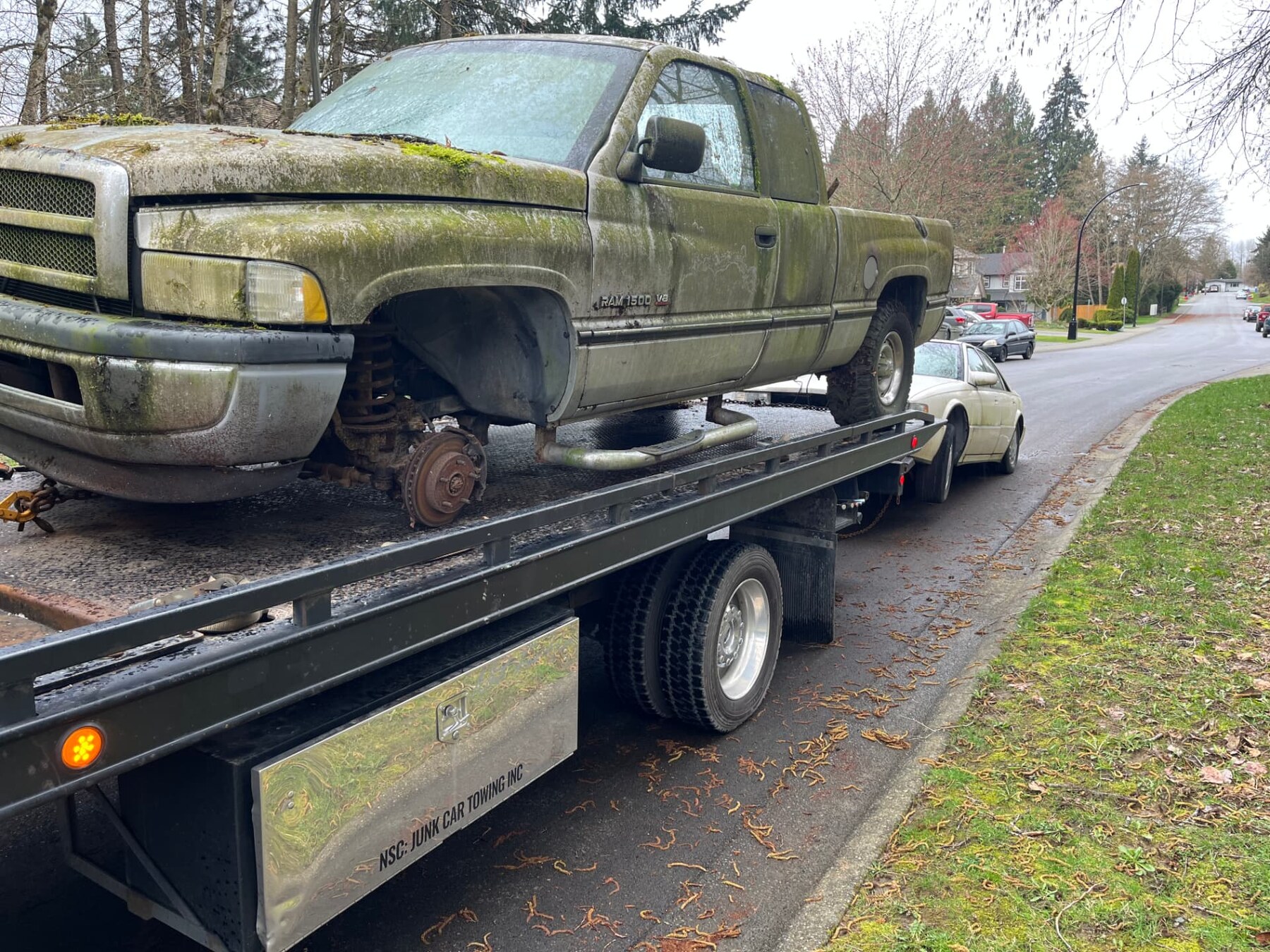 Moss-covered Dodge Ram 1500 loaded on Jay's flat deck during a scrap car removal in Mission, BC